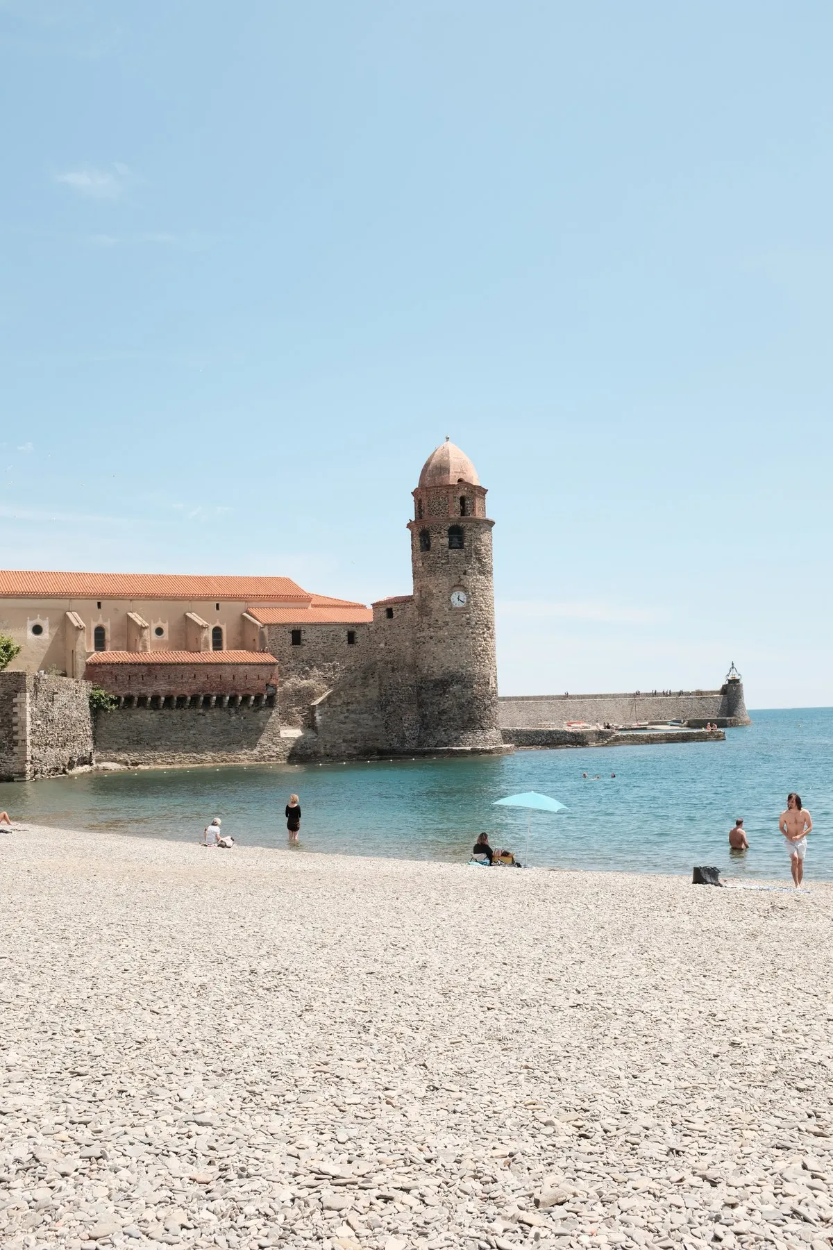 A stone tower beside a sunlit beach and turquoise sea